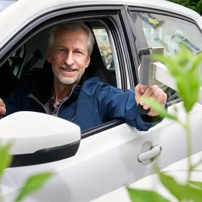 Man sitzt auf der Fahrerseite in einem weissen E-Auto.
