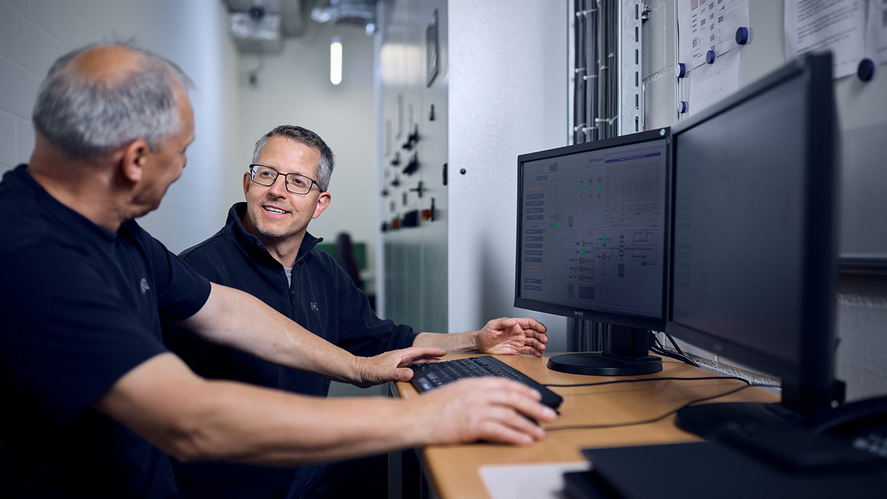 Unsere Datacenter Spezialisten vor dem Computer in der Kältezentrale des IWB Datacenters