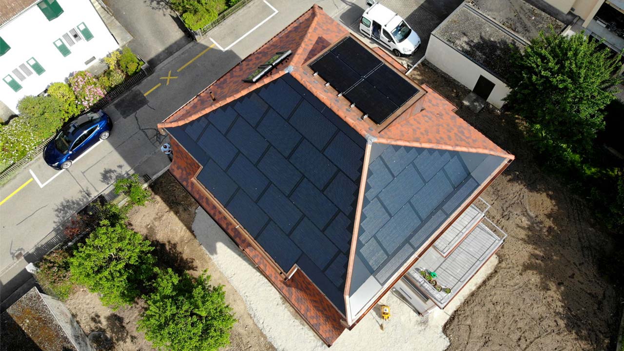 Ein Einfamilienhaus aus der Vogelperspektive. Zwei Dachseiten und ein Erker sind mit Solarpanels bedeckt.