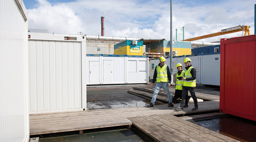 Philipp Frey, Ingela Lakatos und Beat Spengler sind auf der Baustelle zu Fuss unterwegs, wo künftig die Abwasserreinigungsanlage stehen wird. Um sie herum sie Baucontainer.