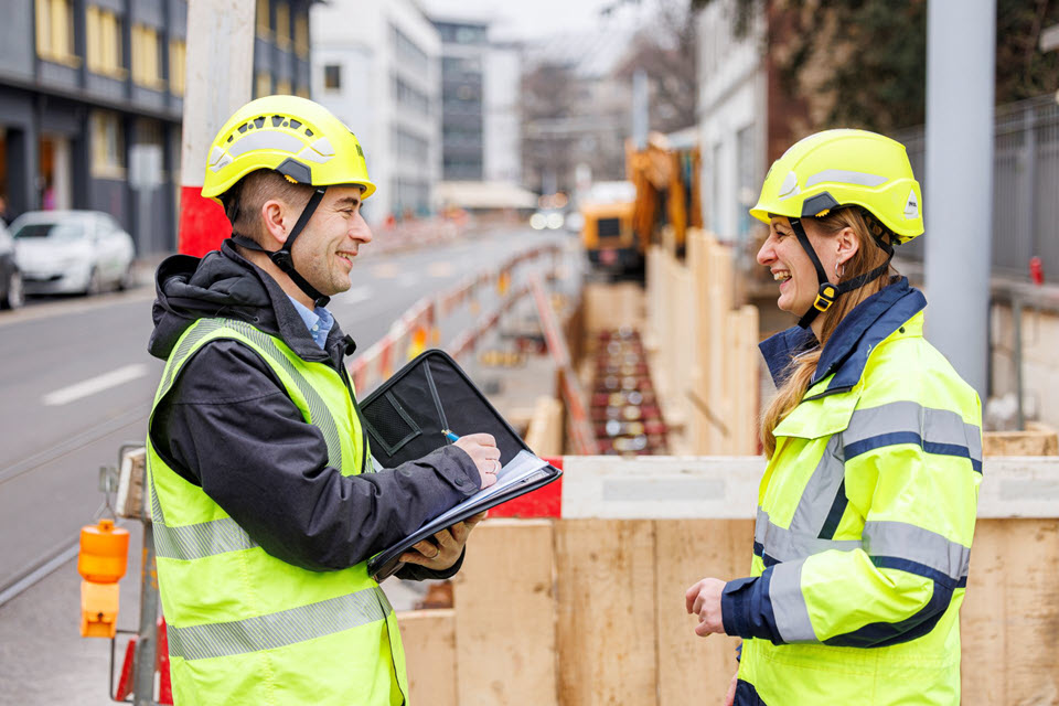 Mann und Frau im Gespräch vor neben einem Baugraben.