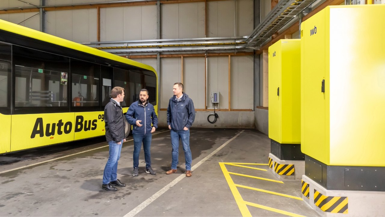 Roman Stingelin von der AAGL und die Mitarbeitenden von IWB stehen vor zwei der fünf neuen gelben Leistungseinheiten..