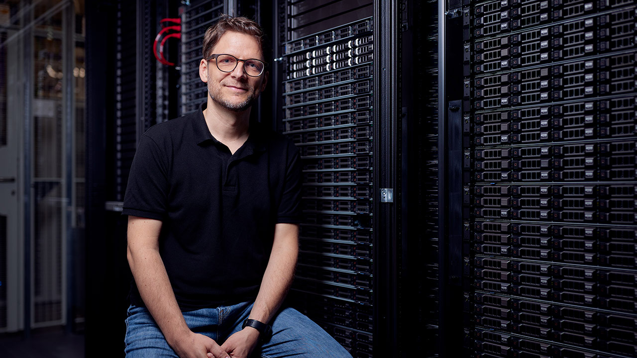 Ein Mann im Datacenter Cage neben einem Server Rack