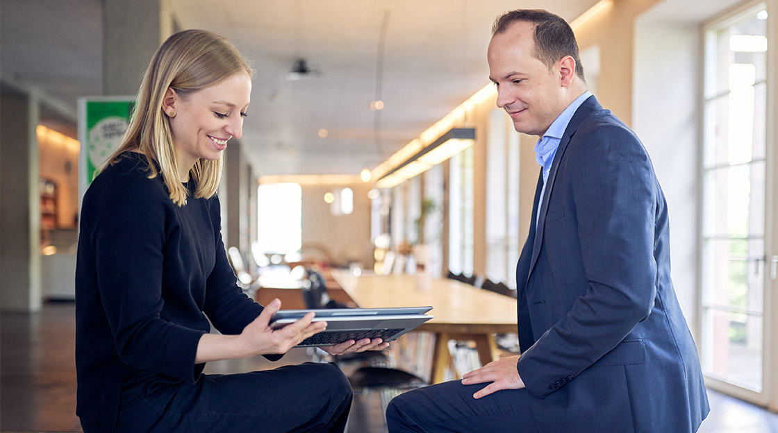 Laura Walter & Alain Gehrig sitzen sich gegenüber und besprechen den Stromverbrauch der Schweizer Jugendherbergen am Tablet.