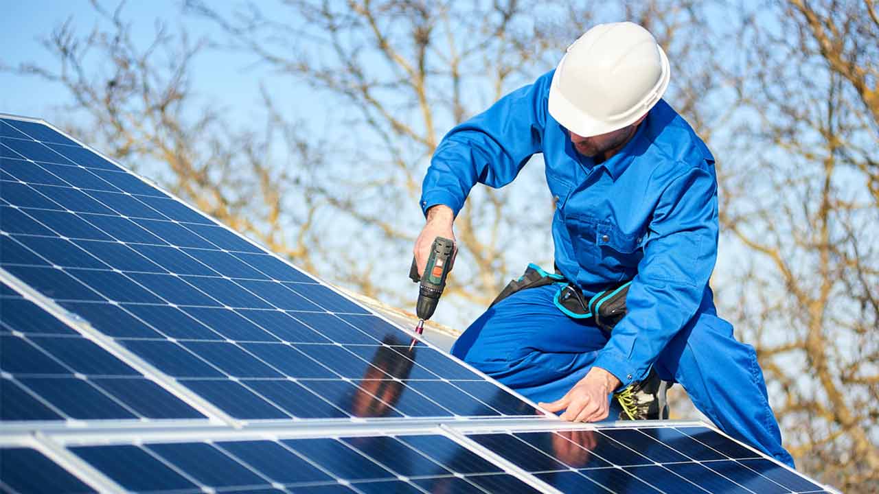 Mann baut auf dem Dach die wichtigsten Komponenten einer Solaranlage zusammen.
