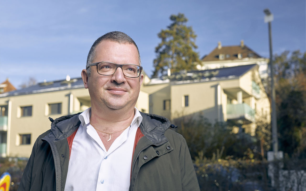 Mann blickt vor Mehrfamilienhaus in die Ferne